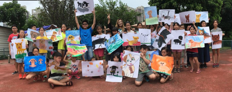 新北市府在板橋動物之家舉辦狗狗節寫生，旅美藝人畫家張富美也到場示範指導，與小朋友一起展示作品。
   圖：新北市動保處提供                        