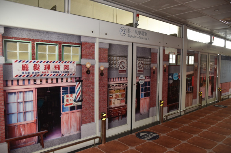  桃園機場公司運用裝置藝術壁貼宣導飛安，將兩航廈管制區外的電車月台，變身為1970年代的老臺灣老街景。   圖：桃機提供