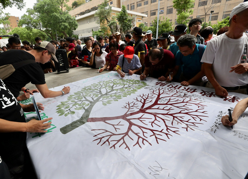 「以核養綠」公投行動小組16日在台北舉行「以核養綠、深耕鄉里、公平選舉」大會，不少民眾到場聲援，在海報上簽名表達支持。   圖 : 中央社