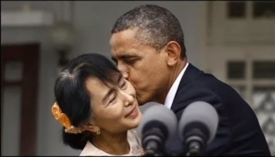 美國前總統歐巴馬（右）訪問緬甸期間，親吻翁山蘇姬臉頰，招致緬甸保守派批評，演變至今，更導致1名作家入監。   圖：翻攝Yputube/Movie News