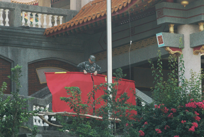 魏明仁在清晨7:56舉行降五星旗儀式，隨後並將碧雲禪寺正前方的四面五星旗和解方軍旗收下捲起來（3）。   圖：張良一/攝