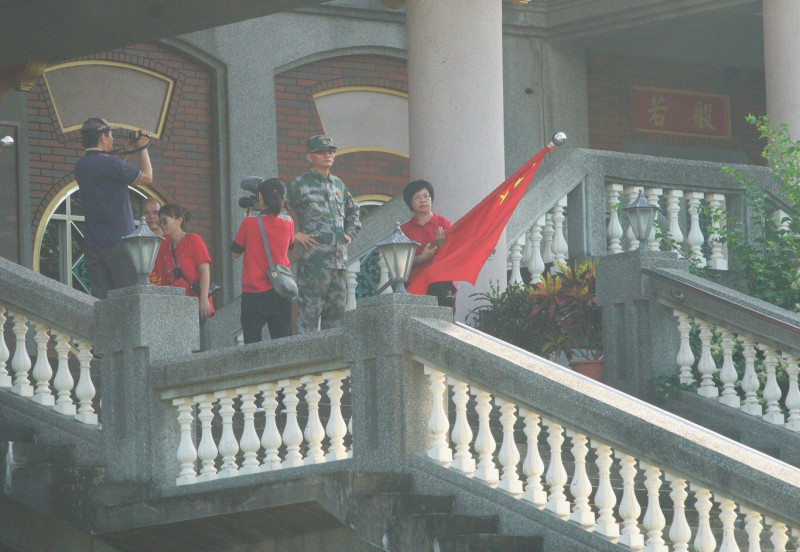 魏明仁在清晨7:56舉行降五星旗儀式，隨後並將碧雲禪寺正前方的四面五星旗和解方軍旗收下捲起來（5）。   圖：張良一/攝