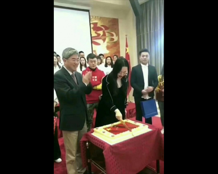 一名站在中國駐保加利亞大使張海舟身旁的女子手持長刀，從中間切開五星紅旗圖案的蛋糕，張海舟則在一旁微笑鼓掌。   圖：翻攝自Youtube
