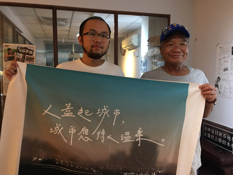 「人生百味」共同創辦人巫彥德(左)與徐大哥(右)拿著標語－「人蓋起城市，城市應待人溫柔」。   圖：詹婉如／攝
