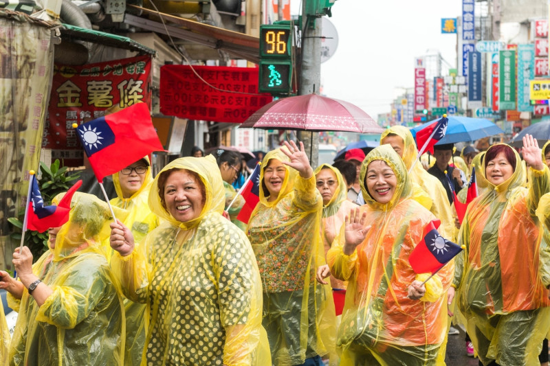 雖然天雨，還是有不少眷村媽媽們穿著雨衣踩街與社區熱情互動。   圖：桃園市政府／提供