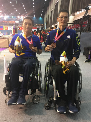 吳振勝（右）和殷建平（左）13日在2018印尼亞洲帕拉運動會桌球男子團體賽輪椅組第3級，循環賽最後一役以2比0擊敗哈薩克，替中華亞帕運桌球代表隊再添一銅。   圖/中央社(殘障體總提供)