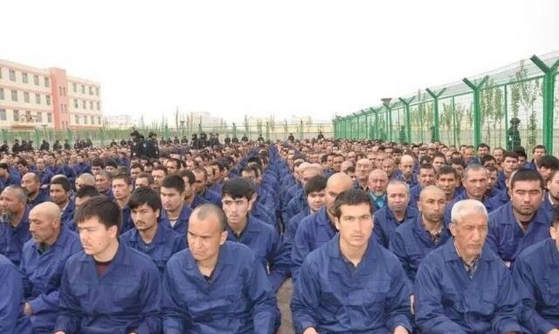 新疆再教育營的「學員」，穿著囚服，關在鐵絲網內。資料照片。   圖：翻攝自新疆司法行政微博