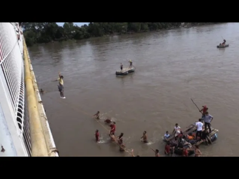 移民高呼「我們可以！」和「墨西哥！墨西哥！」，他們稍早爬上或拆毀一連串路障，湧上大橋。部分移民使用繩索跳下橋，游過蘇奇亞提河（Suchiate River）或搭乘平常渡河使用的木筏。   圖：翻攝自Youtube