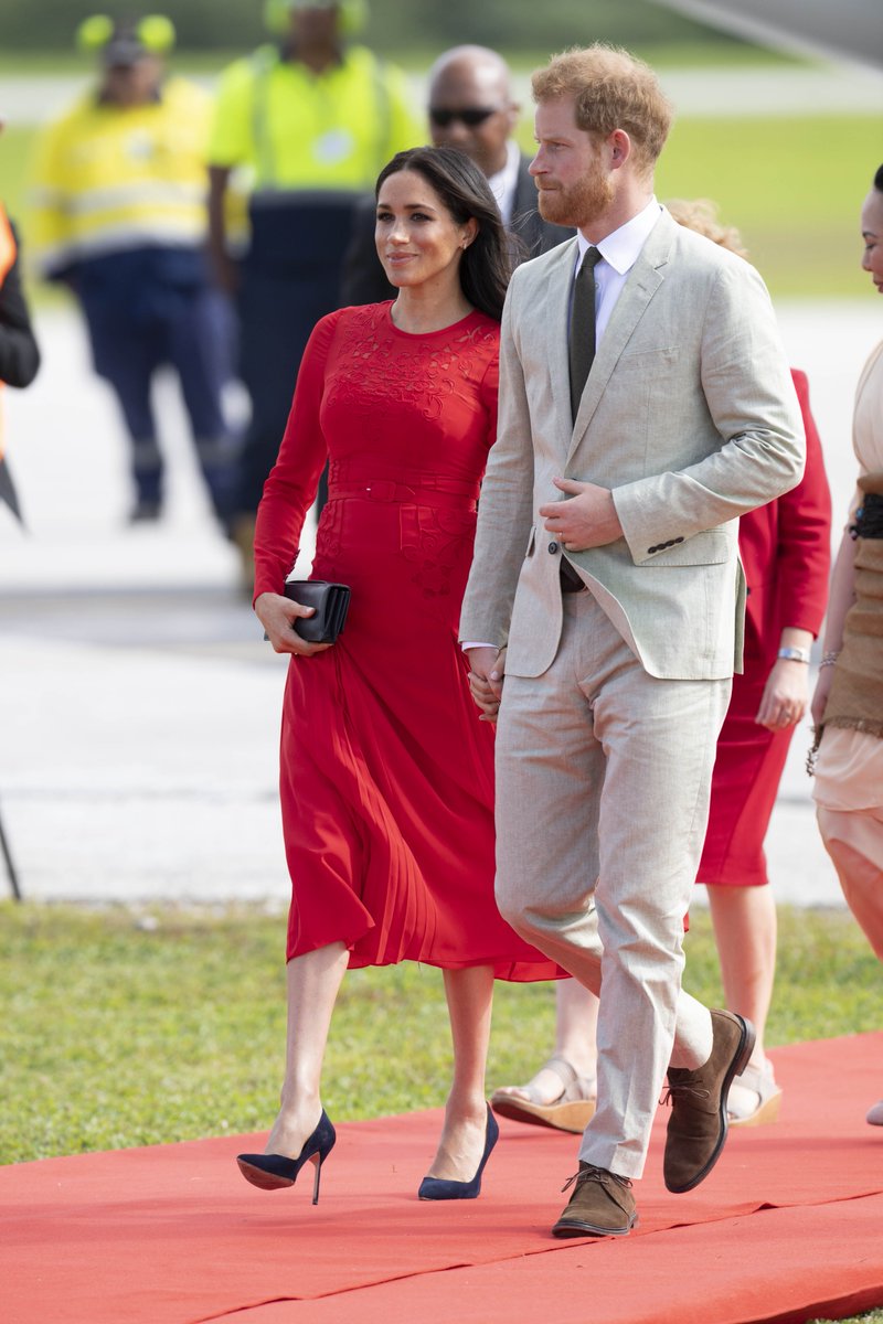 英國王妃梅根馬克爾（左起）隨著哈利王子訪問東加王國，一襲紅洋裝非常亮眼，卻意外露出衣服標籤。   圖：翻攝Meghan Markle Fan I meghanmarklefan.com ‏推特