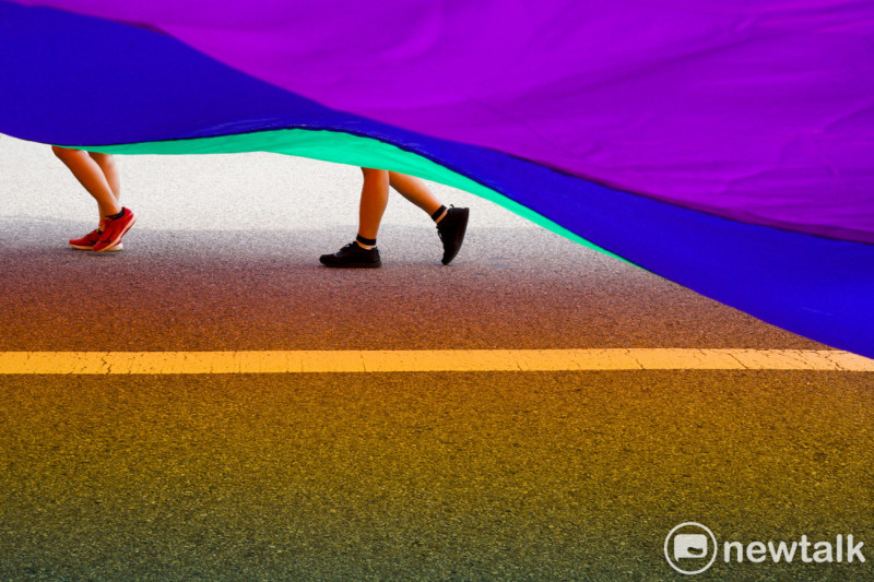 參加同志大遊行的人一起舉起巨幅彩虹旗走上街頭。   圖：張良一/攝