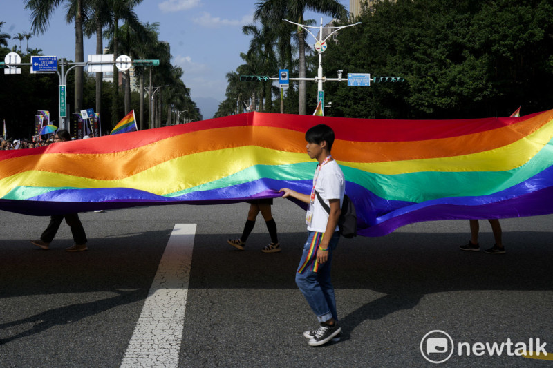 參加同志大遊行的人一起舉起巨幅彩虹旗走上街頭，為同志應有的權利表達訴求。   圖：張良一/攝