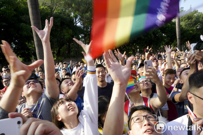 年輕同志們張開手臂抓取從車上丟下來的彩虹旗。   圖：張良一/攝