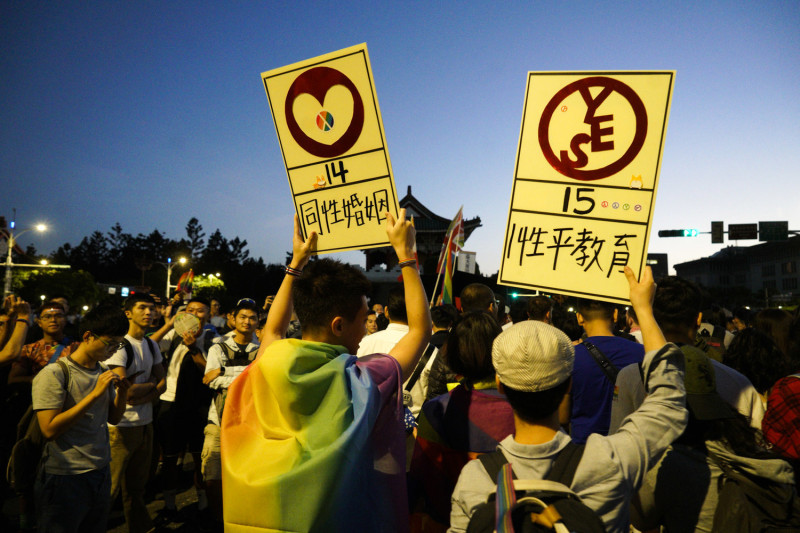 兩位同志大遊行的志工高舉同意『同性婚姻』和『性平教育』公投的牌子，提醒參與遊行群眾不要忘了11月24日去公投。   圖：張良一/攝