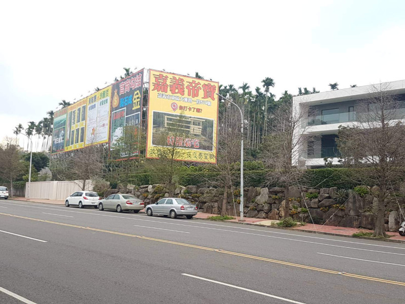 嘉義市建商黃朝雲位於大雅路上的豪宅旁，遭人架設廣告大肆抨擊。   圖：黃朝雲/提供