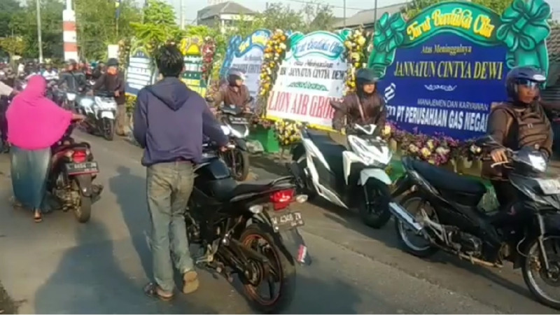 印尼摩托車騎士經過獅航罹難者黛薇老家時，紛紛下車牽行車輛致哀。   （圖取自facebook.com/bahana.patria.3）