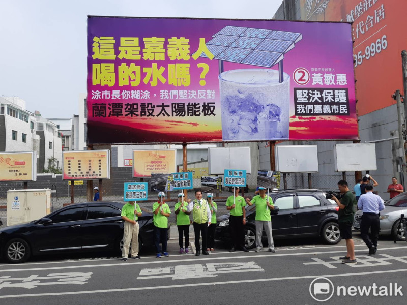 國民黨嘉義市長候選人黃敏惠懸掛「蘭潭架設太陽能板」競選廣告看板，對手之一的涂醒哲7日在看板下舉行記者會反擊。   圖：蔡坤龍/攝