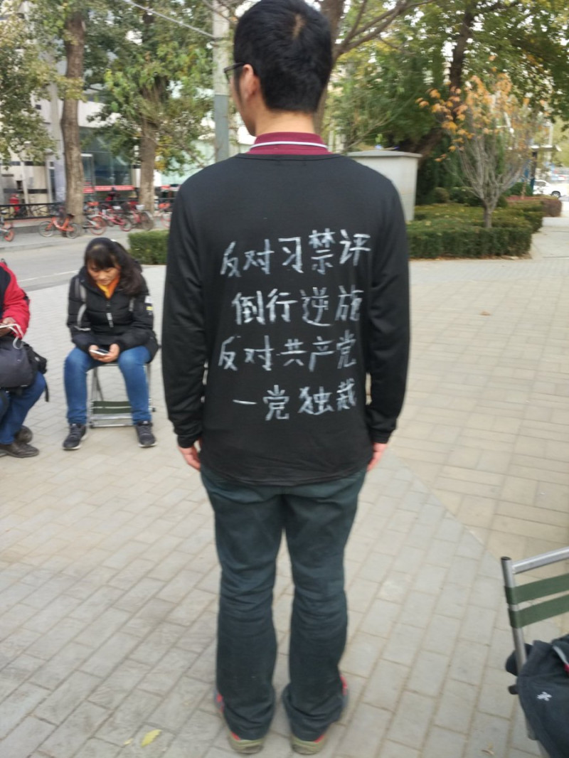 中國青年祁怡元穿著黑色上衣，背後寫著：「反對習禁評倒行逆施」，高呼要求結束共產黨一黨獨裁。   圖：翻攝付振川推特