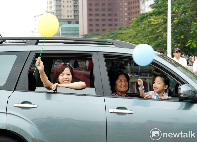 民眾乘車經過高雄WeCare氣球大遊行現場，孩童於車內舉起氣球。   圖：張良一／攝
