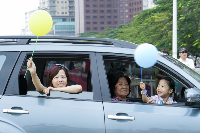 坐在車上的民眾拿著氣球和參加we care 遊行的民眾相呼應。   圖：張良一/攝