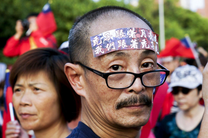一位韓國瑜的支持者在額頭上貼上「禿子跟著月亮走 我們跟著禿子走」的貼紙。   圖：張良一/攝