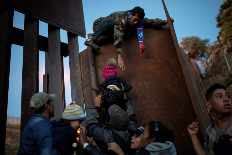 美墨邊境圍牆。圖為一個已登上圍牆的難民，正協助他偷渡客越過柵欄。   圖 : 達志影像/ 路透社