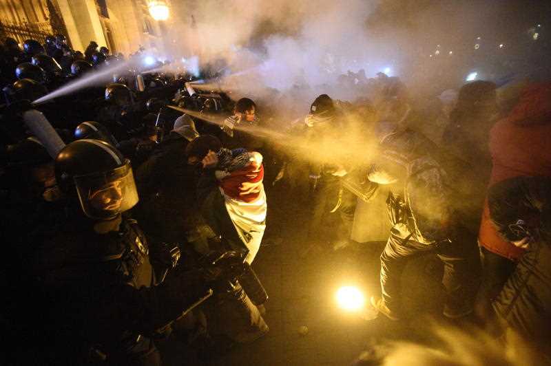 約2000名示威者聚集在匈牙利國會外，朝鎮暴警察丟擲瓶罐和煙幕彈，警方則以催淚瓦斯回擊。   圖/翻攝自EPA
