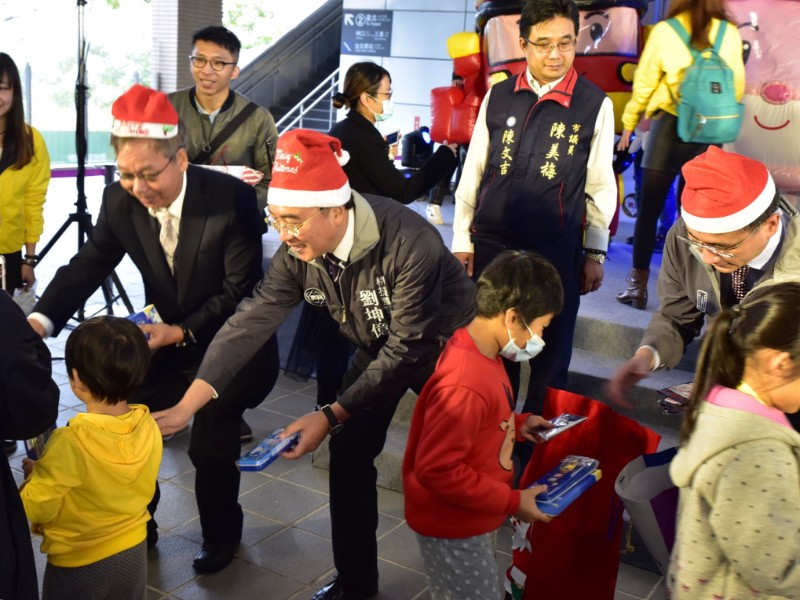 桃園捷運公司董事長劉坤億扮起聖誕老公公發禮物給小朋友，提前歡度耶誕節。   圖：桃園捷運公司／提供