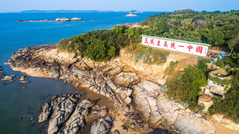 大膽島心戰牆上寫著「三民主義統一中國」的巨型的軍事標語，是島上著名的觀光景點。   圖：金門旅遊網／提供