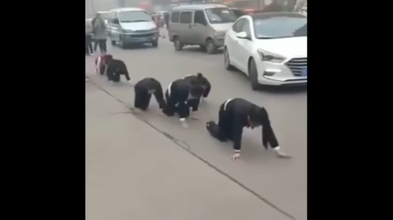 中國山東一間公司迫使女員工街頭集體跪地爬行，引發民眾與警方關注。   圖：翻攝自youtube