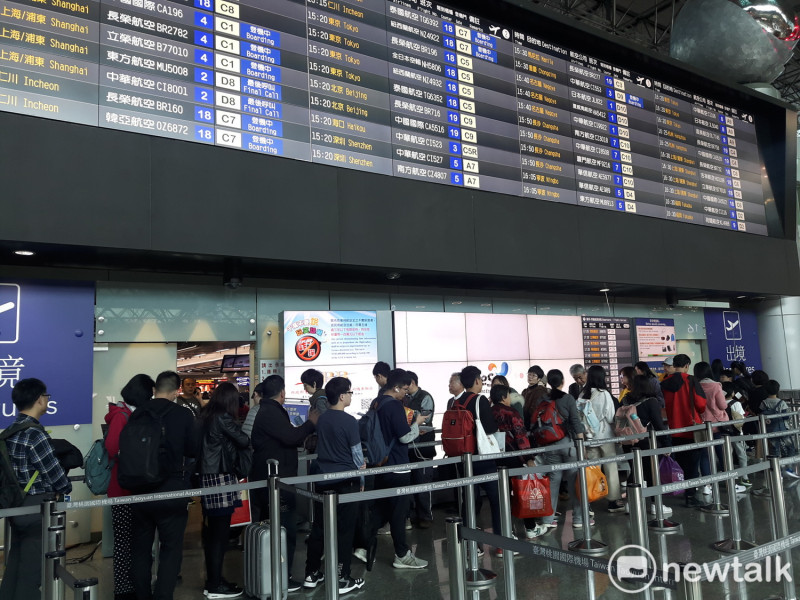 桃園機場出國人潮增多，民眾排隊等待出境通關。   圖：林昀真／攝