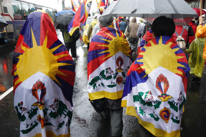 310西藏抗暴日60週年遊行參加者將西藏國旗披在肩上前行。   圖：張良一/攝