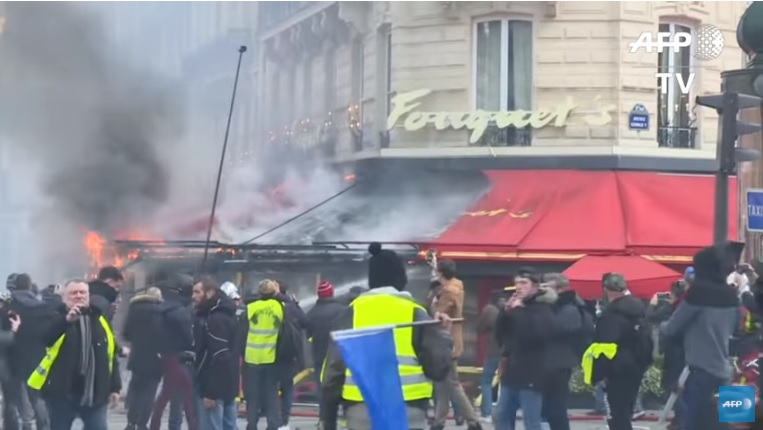 法國「黃背心」運動第18波街頭行動再度混入暴力分子，放火燒店舖及書報亭、趁亂打劫。   圖：翻攝Youtube