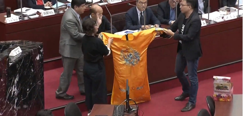 高雄市議會今日開會時，民進黨團總召李喬如及市議員黃文益準備了一件黃袍送給高雄市長韓國瑜。   圖：翻攝自youtube。