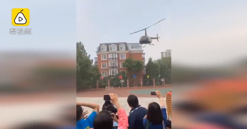 中國北京海淀區楓丹實驗小學有一名陳姓家長，為了配合孩子學校的科技節活動，派公司2名機師將直升機飛到孩子的學校，降落在操場。   圖：翻攝自梨視頻