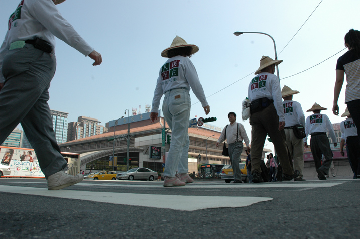 參與運動的人士頂著烈日，一步一步行經台北車站，身旁的車潮來來往往。   圖：邱萬興/攝影