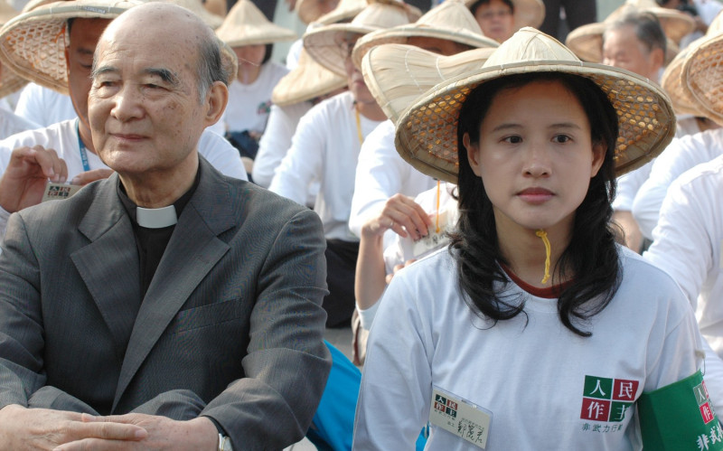 高俊明牧師（左）與現任文化部長鄭麗君（右）以及一群參與人民作主運動的人士一同坐在台北市龍山寺前。   圖：邱萬興/攝影