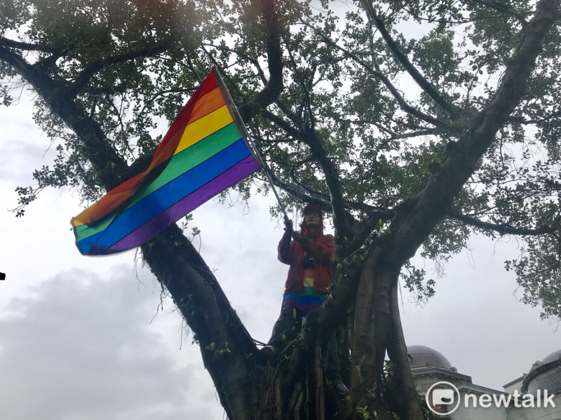 長期投入同志運動的祁家威在高處揮舞著彩虹旗。   圖：周煊惠 ／攝