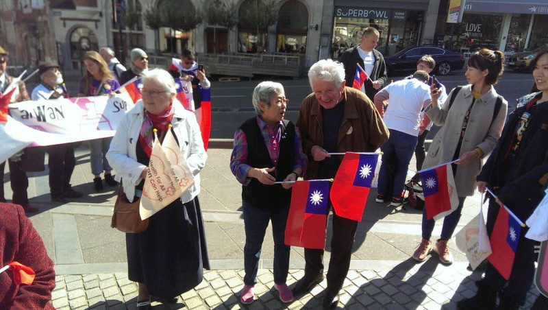 許多僑胞及留學生手持中華民國國旗及各種支持台灣參與WHO標語牌。   圖：何康美提供