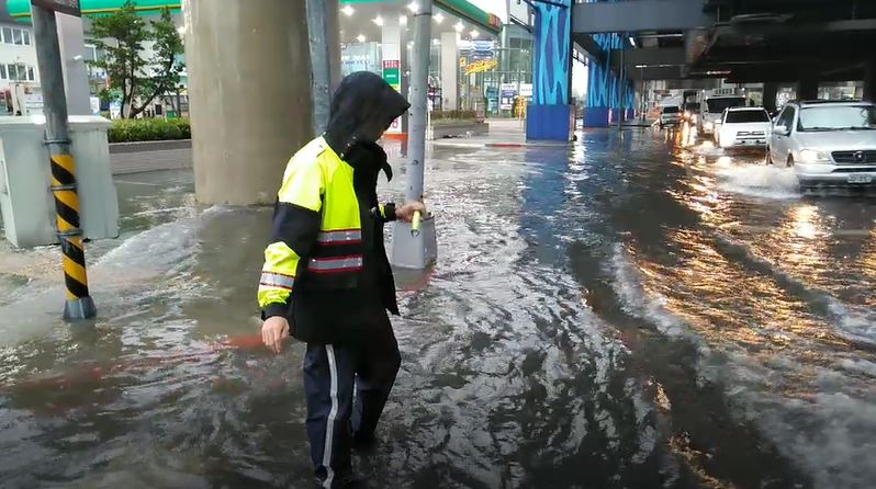 因雨勢過大造成Ａ８捷運站周邊積水嚴重，警員站在積水中指揮車輛通行。   圖：龜山分局／提供