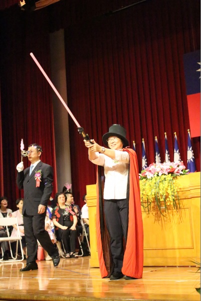 竹林中學校長顏麗珠手持星戰光劍、頭頂圓桶高帽、身繫披風，變裝引領導師們進入畢業典禮會場。   圖：竹林中學提供 