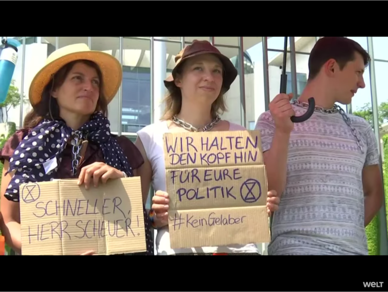 氣候變遷倡議團體「反抗滅絕」數十名德國抗議者今天用鎖鏈把自己拴在總理府前方的欄杆，要求總理梅克爾（Angela Merkel）宣布進入「氣候緊急狀態」。   圖：翻攝自Youtube