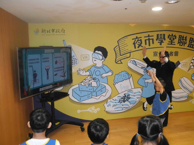 新北市副市長吳明機和小朋友在「夜市學堂聯盟」記者會體驗科技射箭賽，結果以0：140大敗，「笑」果十足。    圖：王峻昌/攝