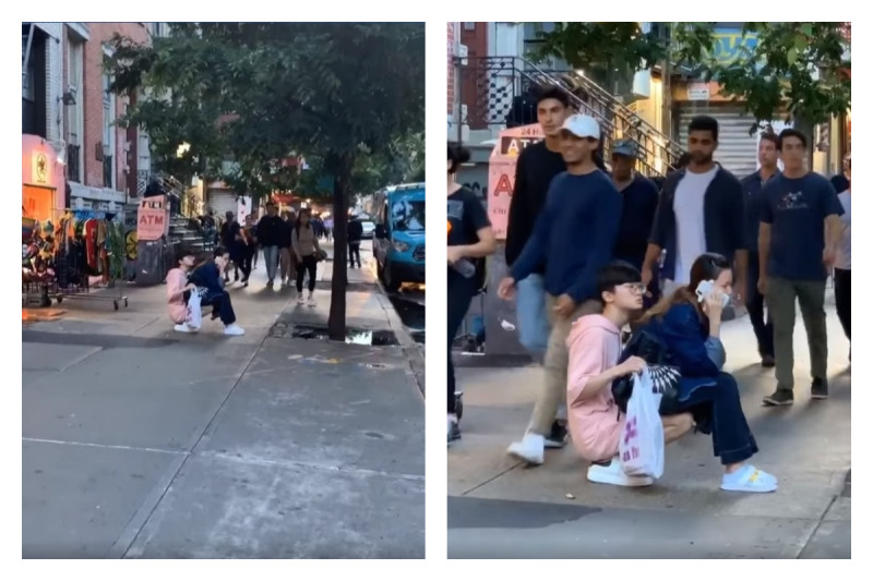 一對情侶大喇喇地坐在路中間，男友蹲著讓女友坐在大腿上講電話，讓網友好傻眼。   圖／翻攝自 What Is New York 臉書影片