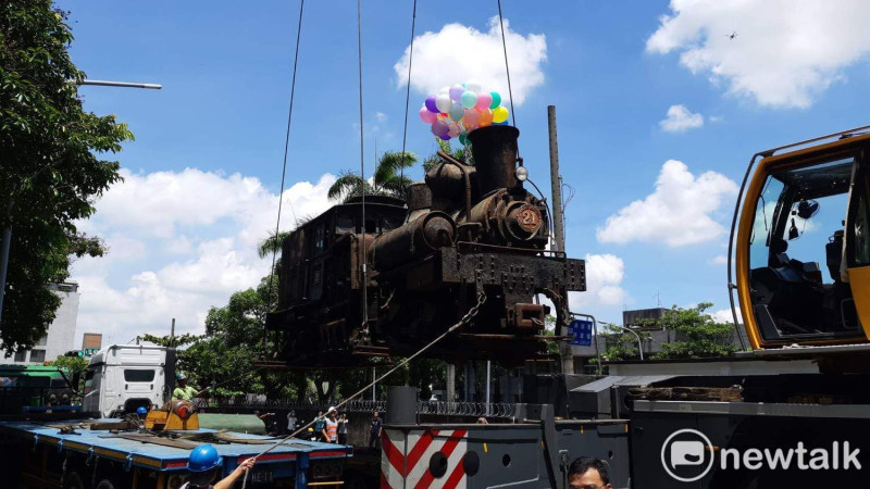 工作人員將老火車頭吊上貨車，準備送往嘉義車庫園區維修。   圖：蔡坤龍/攝