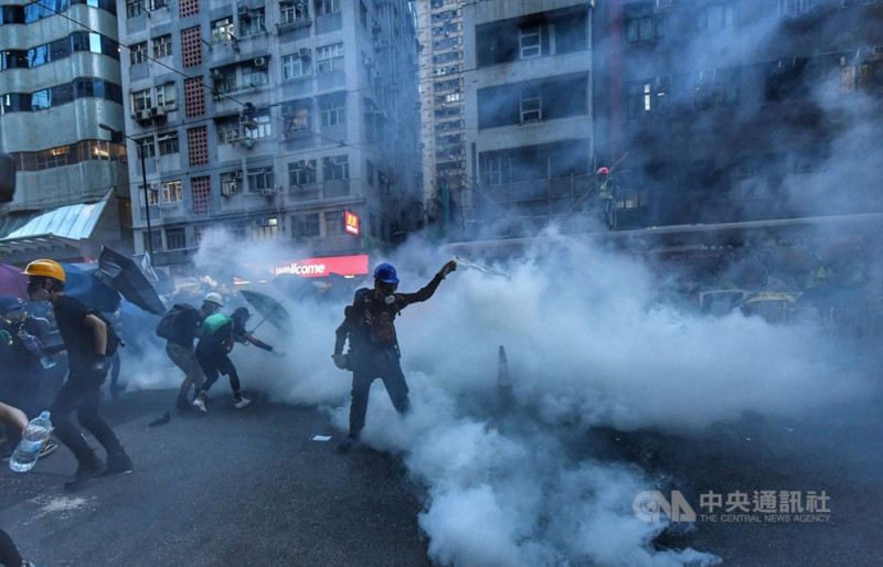 香港28日中環遮打花園追究警方用槍集會，演變為大規模「自主」遊行，香港警方晚間7時高舉黑旗、隨後施放催淚彈清場，現場煙霧瀰漫。   圖：中央社提供。