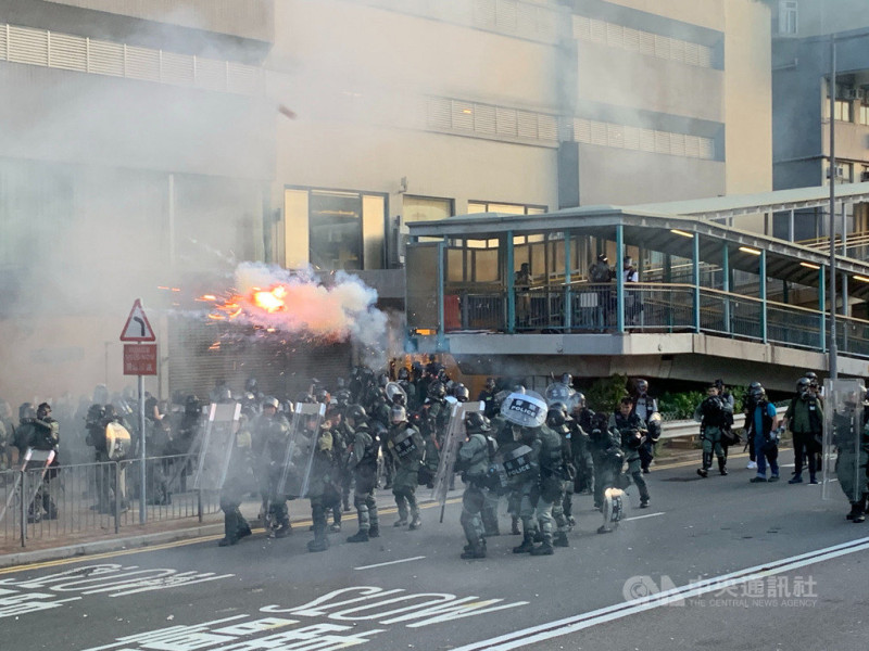 香港反送中自主遊行的部分示威人士，28日下午包圍中聯辦，港警派出大批防暴警察鎮守，並在晚間7時高舉黑旗、隨即施放催淚彈進行清場。   圖：中央社提供。