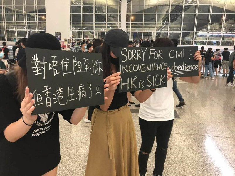 香港青年在機場高舉標語，向這2天行程受阻的旅客致歉。   圖：翻攝自ChunTing Lau臉書