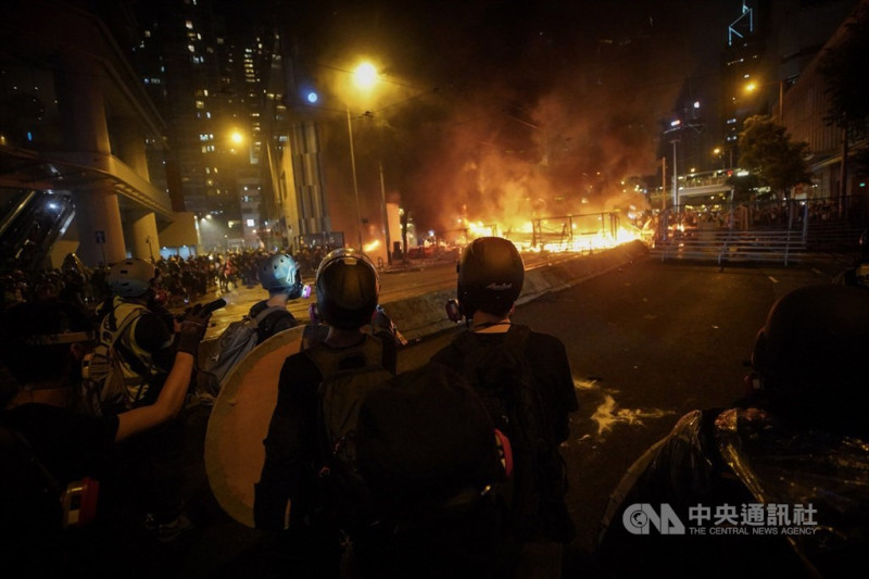 香港反送中運動31日傍晚上演暴力抗爭場面，除警方發射催淚彈、出動水炮車外，示威者也頻丟汽油彈等，雙方對峙至入夜仍持續，灣仔一帶街道燃起熊熊火光。   圖/中央社