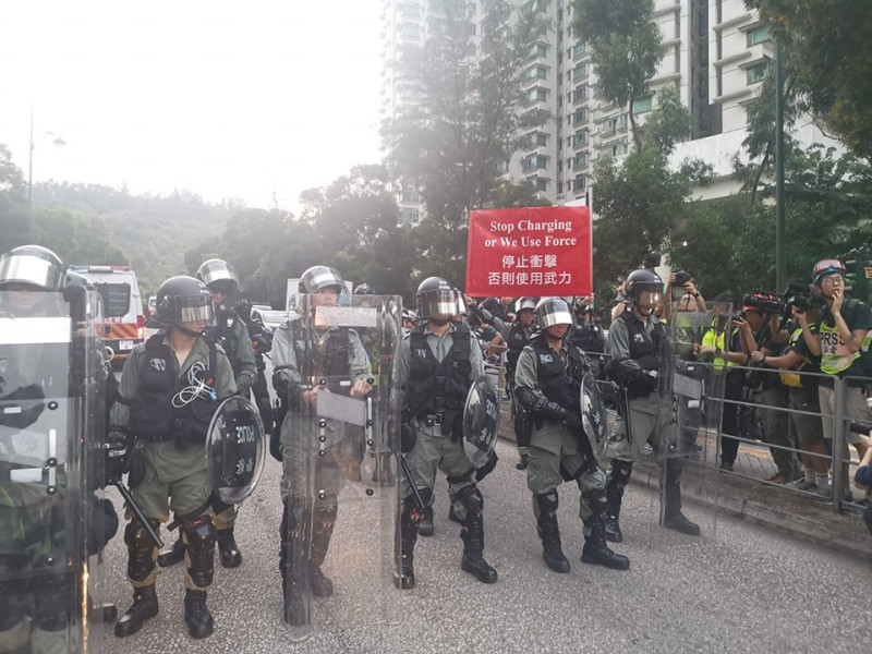 香港「反送中」示威，東涌消防局外，有民眾向警員投擲水瓶，防暴警從藍旗、黃旗，一路舉到紅旗警告示威者。   圖：翻攝東涌居民關注組臉書