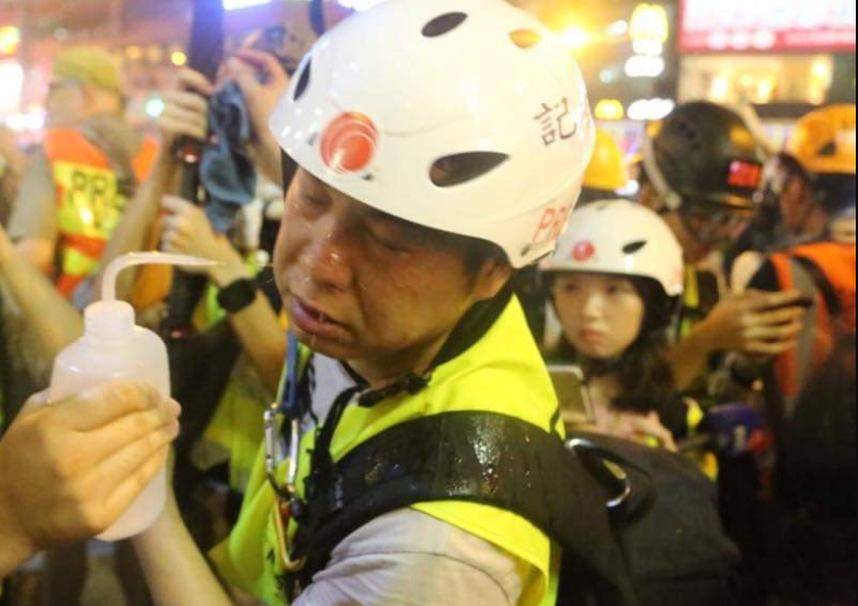 警方直接向示威者臉上噴胡椒噴霧，臉部受傷的記者用水清洗。   圖：翻攝香港浸會大學學生會編輯委員會